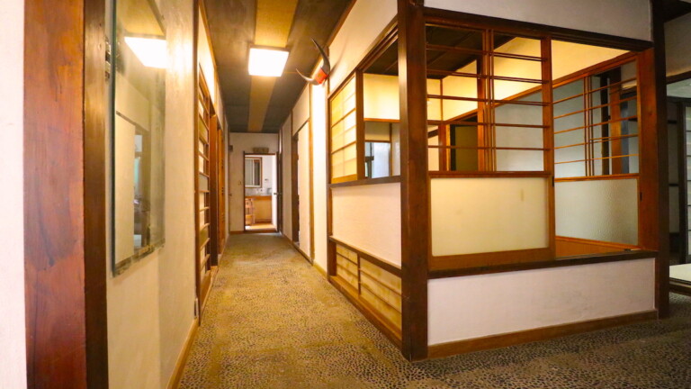1階廊下は白い漆喰壁と洗い出しの床 昭和レトロなあたみの旅館の廊下